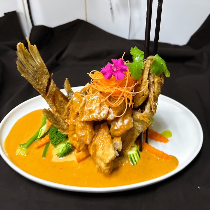 aWhole crispy barramundi in chu chee curry with vegetables